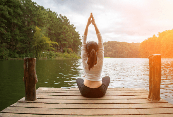 Women doing yoga on a lake dock